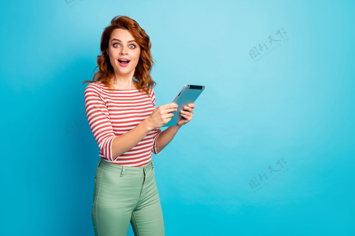 网络激动可爱可爱的可爱女孩的肖像使用平板电脑搜索难以置信的信息印象深刻尖叫哇omg穿好看的衬衫隔离蓝色惊喜时髦新闻