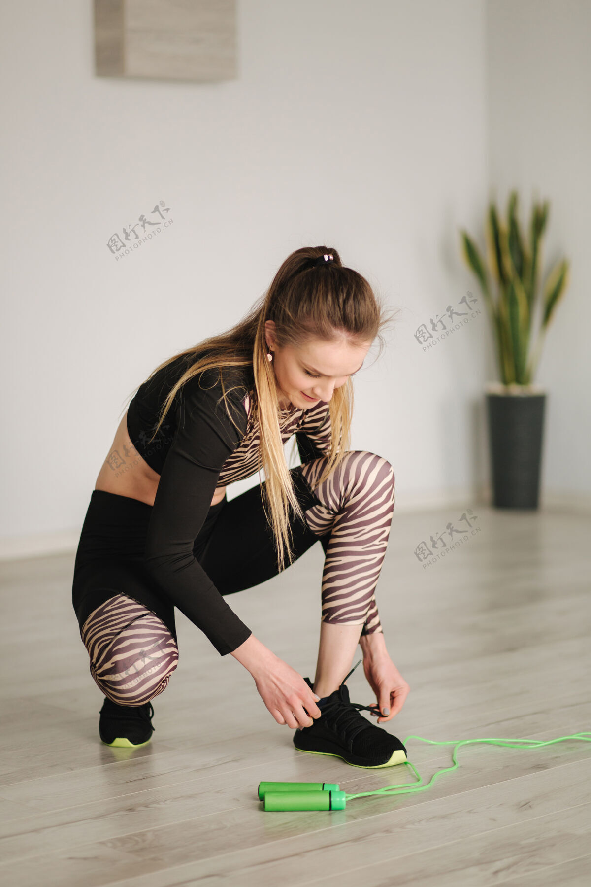 锻炼穿着运动服的女运动员做运动和跳跃绳子女人在工作室系鞋带年轻女人系鞋带