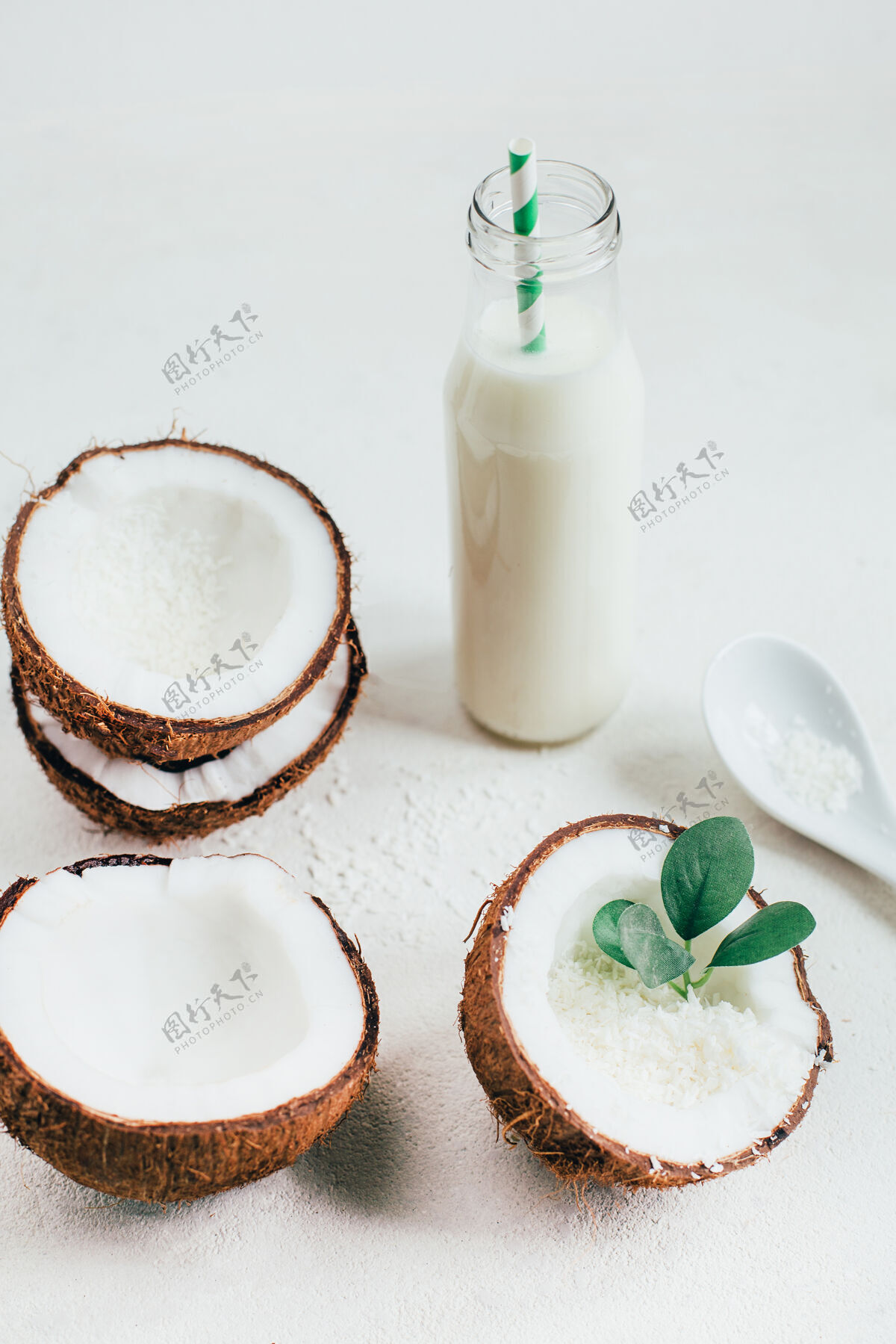 稻草椰子和椰子奶装在一个白色背景的瓶子里饮料叶子桌子