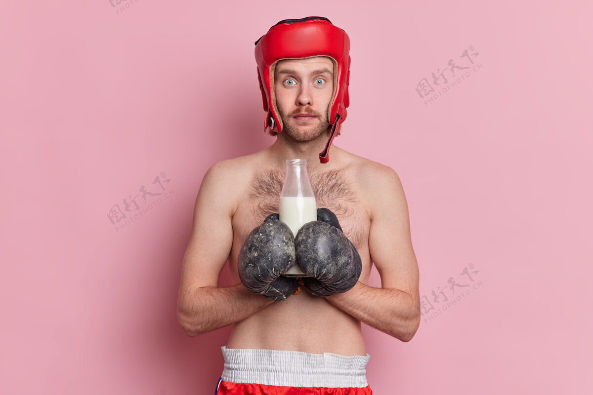 拳击照片中的男拳击手已立志要赢得比赛 备战时戴拳击手套和防护头盔 喝牛奶作为钙源赤膊上阵健身房运动员站立