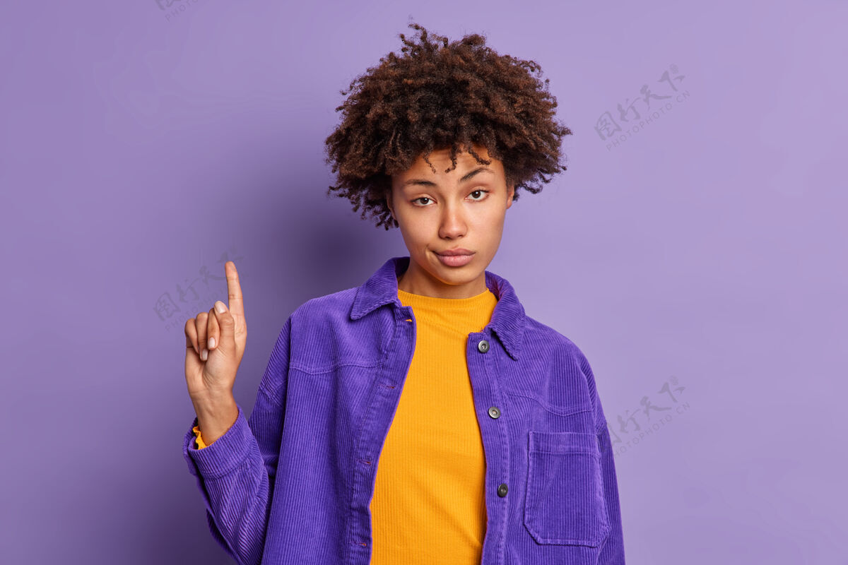 人严肃的非洲裔美国女人有卷发保证你上楼用食指以上指示穿时髦的衣服自然美国指向