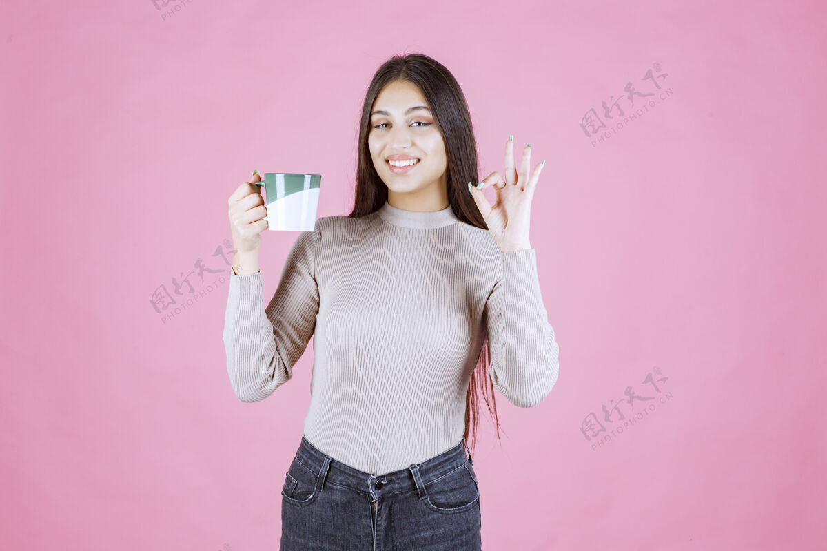 女人一个拿着咖啡杯的女孩在做享受的招牌积极好人类