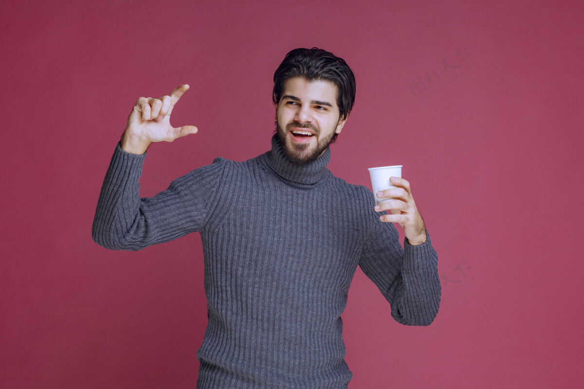 年轻人一个拿着一次性咖啡杯的男人 展示他需要多少人成人人体模特