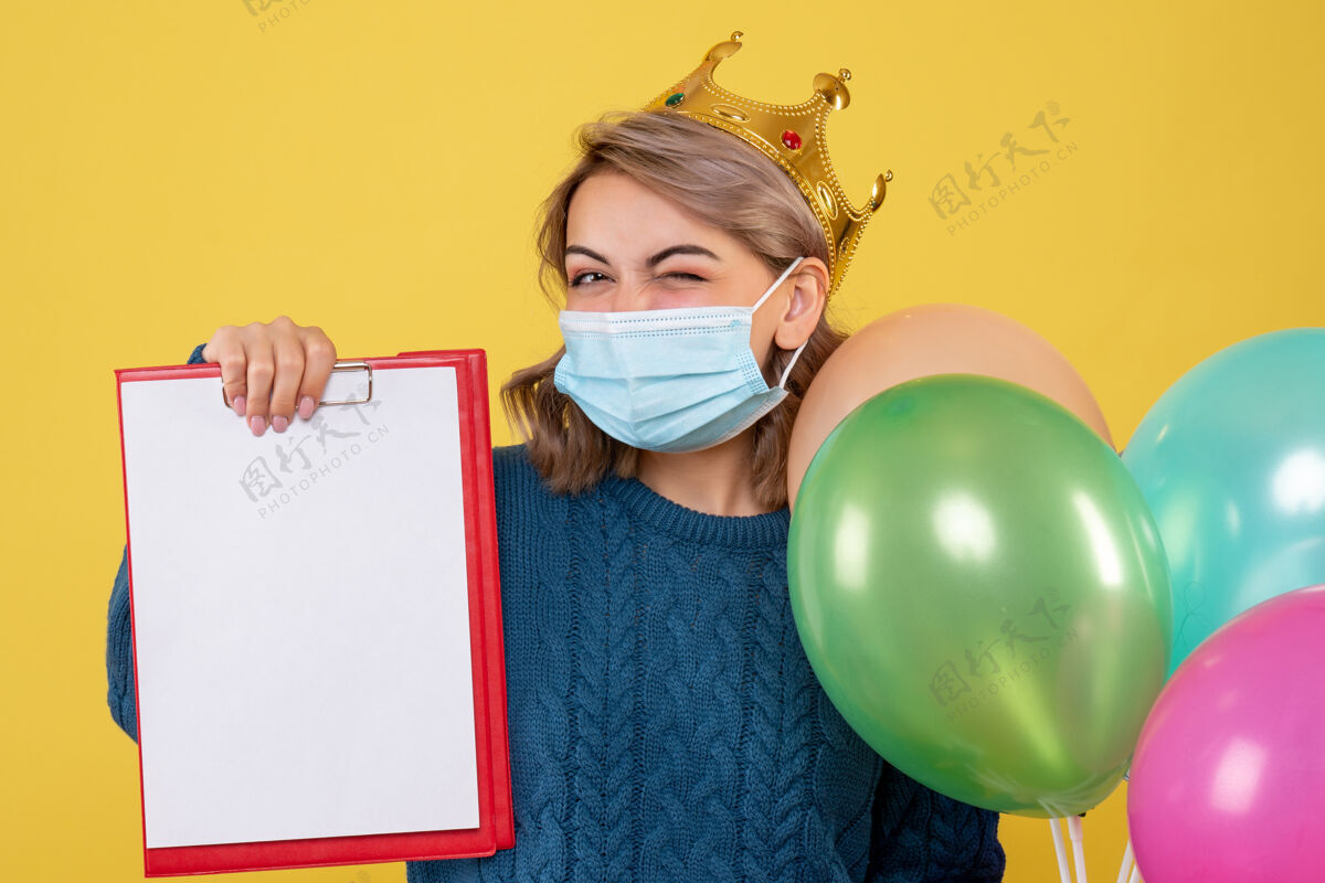 情绪年轻的女性拿着黄色的无菌面具气球脸保护封面面具