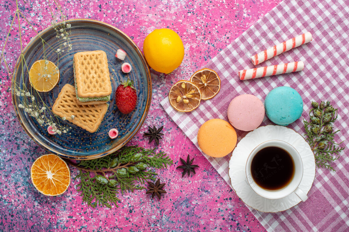 茶俯瞰美味的华夫饼 在粉红色的表面上放上一杯茶和法国马卡龙华夫饼粉末早餐