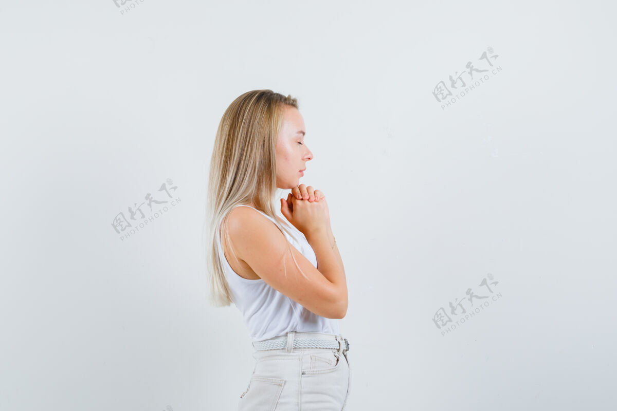 人金发碧眼的女士穿着单衣 裤子紧握着双手祈祷 看起来充满希望肖像手头发
