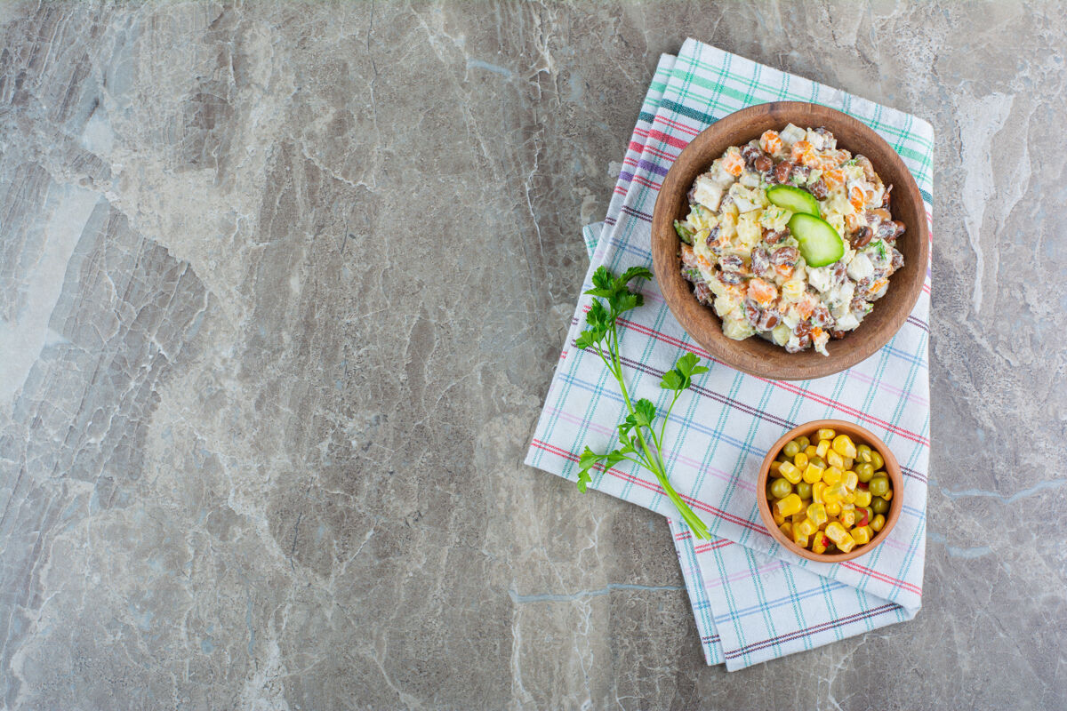 牙粉一碗蔬菜沙拉 旁边是一碗玉米沙拉 放在大理石上的茶巾上顶视图美味蛋黄酱