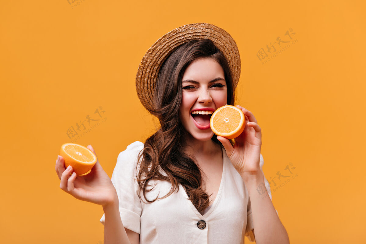 波浪发一幅调皮女孩的肖像 波浪形头发咬着橙色戴草帽的女士在橙色背景上摆姿势女人卷发橙色