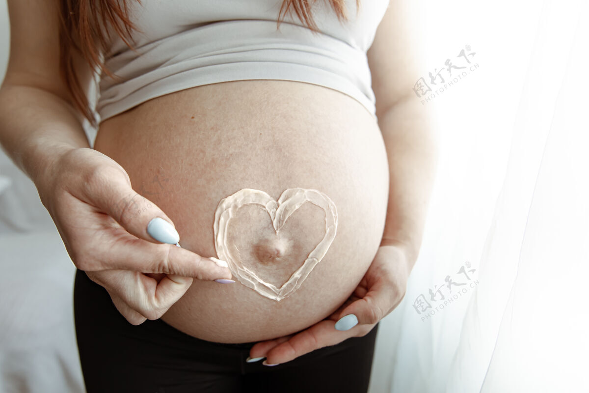 腹部一位未来母亲怀孕最后几个月的裸体腹部特写镜头 涂上了一层心霜爱特写父母