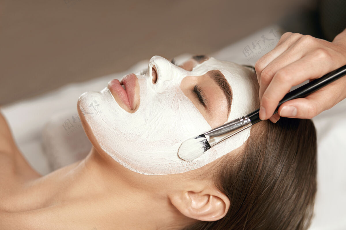 面部护理美丽的年轻女子在美容中接受白色面膜沙龙水疗中心皮肤和身体护理.面部护理美容化妆师美容治疗休息