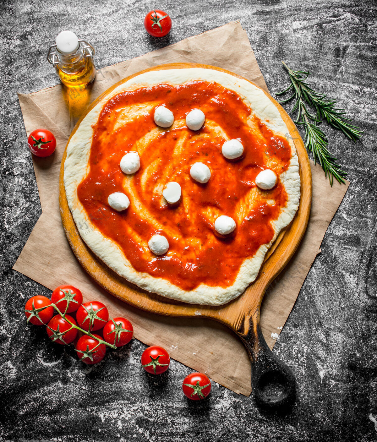 小麦生披萨用意大利干酪和番茄酱在乡下的桌子上擀面团切割迷迭香圆形