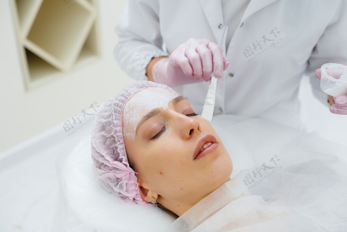 手术一个年轻的女孩在美容办公室正在进行面部皮肤年轻化程序过程面霜丰满