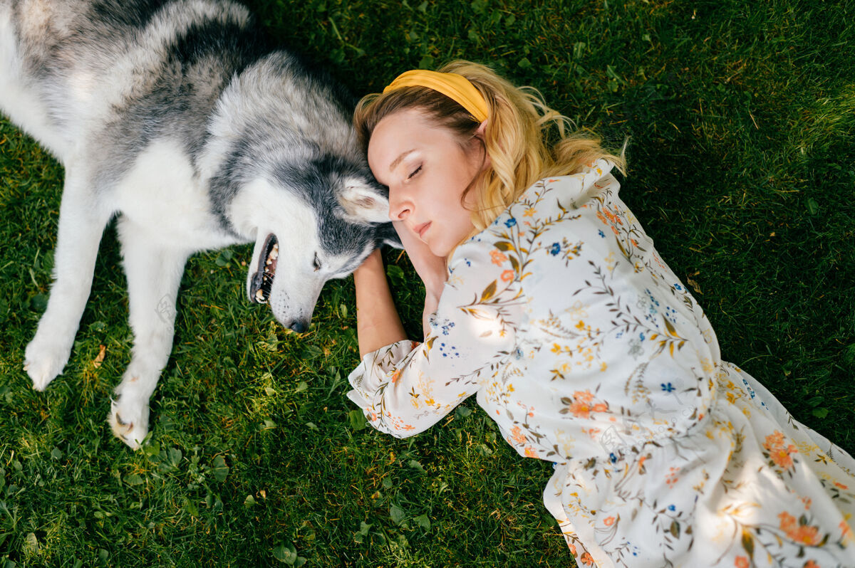 谎言一个年轻浪漫的女人和一条狗躺在草地上睡眠年轻姿势