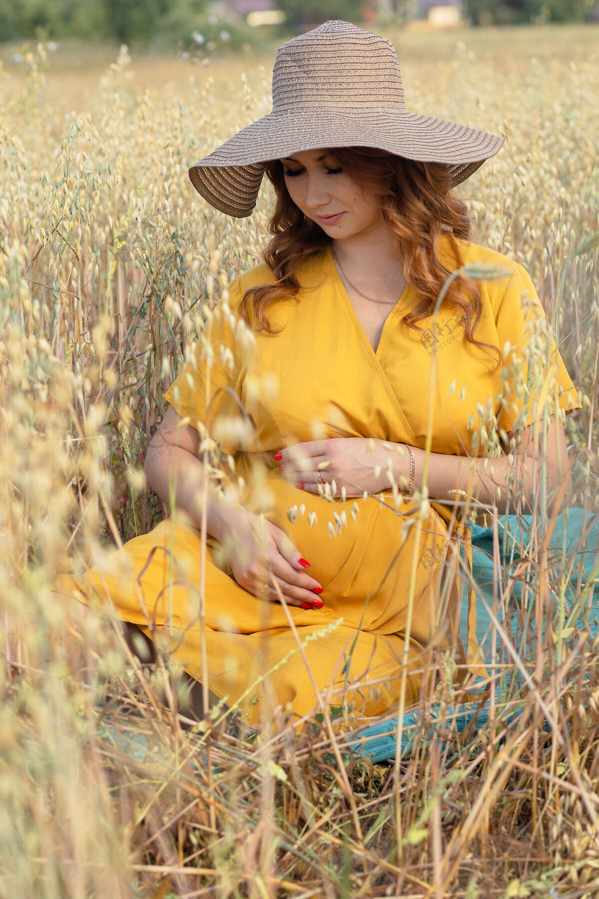 模糊在一个阳光明媚的夏日 一位年轻漂亮的孕妇穿着黄色的裙子 戴着黄色的帽子 走过一片麦田自然肚子风景