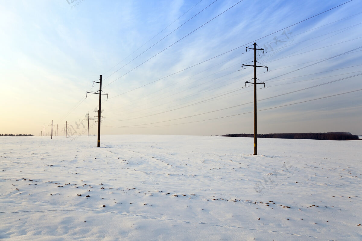 寒冷冬天被雪覆盖的田野在可见的电线杆上日落黄昏日落天空