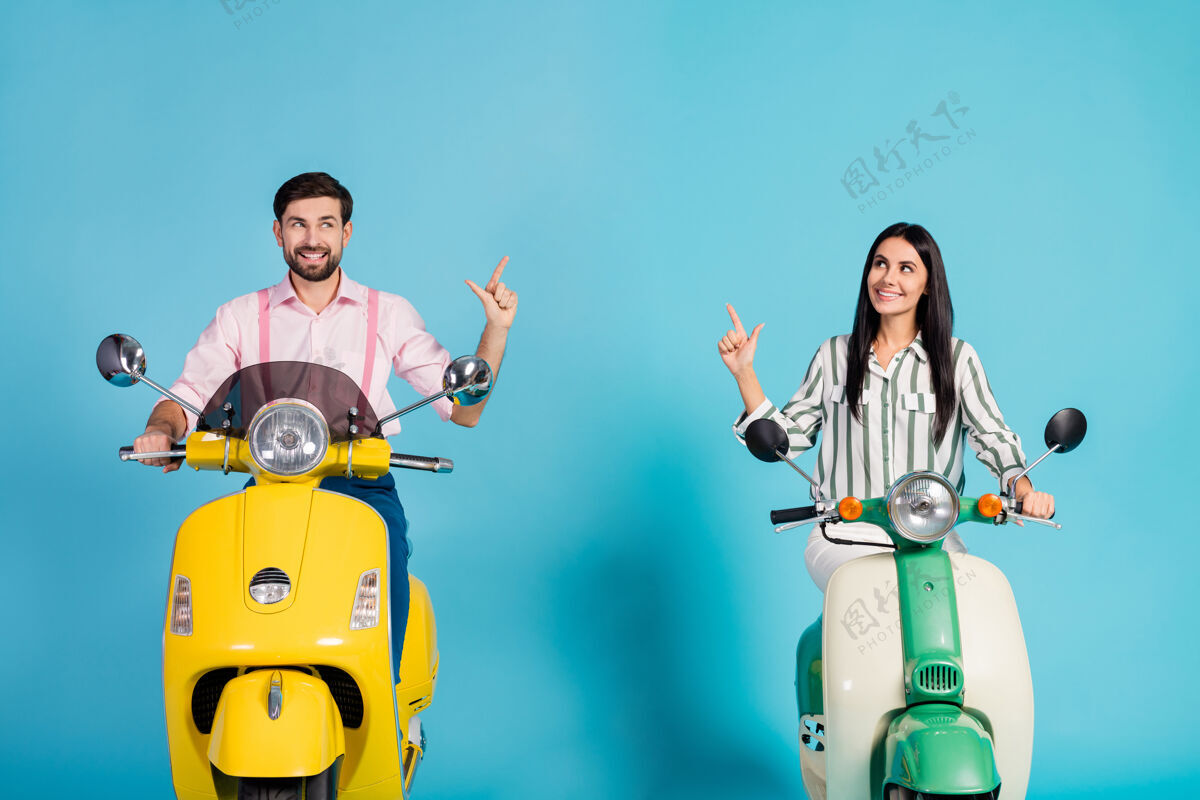 夫妇积极开朗的两人骑自行车骑高速电动滑板车跟路旅行点食指复印空间穿条纹粉色衬衫隔离蓝色墙壁情人关系轻便摩托车