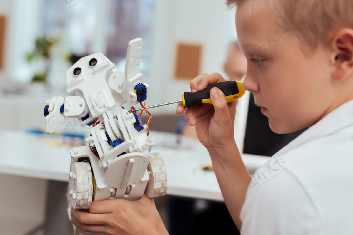 学校专业技术聪明的金发男孩在对技术感兴趣的同时制造机器人教育机器人学习