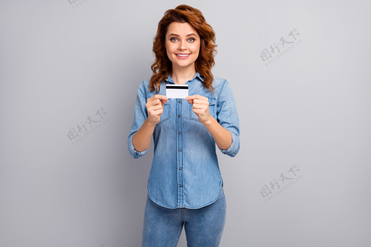 企业家正面开朗女性肖像持银行卡推荐用信用支付服务系统支付购买穿着好看的衣服隔着灰色的墙女孩薪水消费