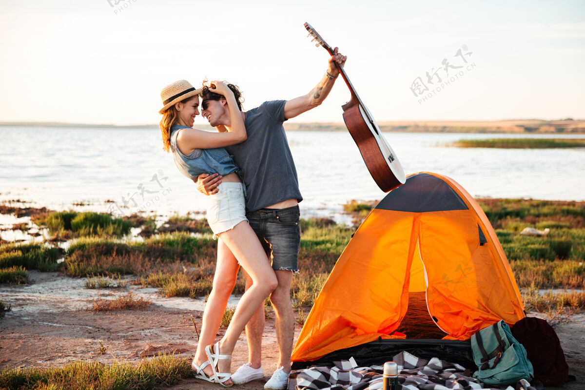 男人在露营帐篷前拥抱的快乐的年轻迷人的夫妇的肖像帅哥年轻冒险
