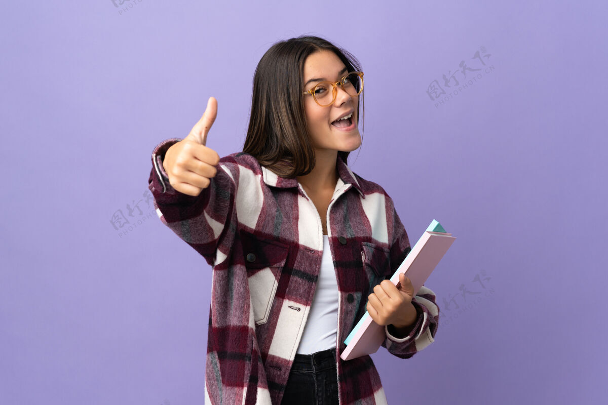 批准一个年轻的女学生因为发生了好事而竖起大拇指孤立在紫色的土地上书成功好