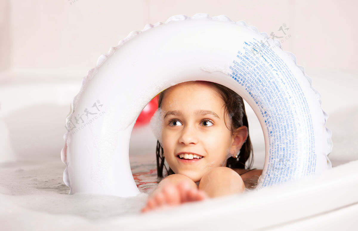 浴缸有趣的小女孩在浴缸里洗澡 浴缸里有一个充气救生圈 水中有泡沫湿欢呼泡沫