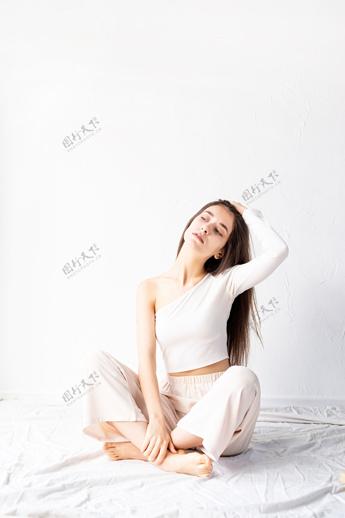 积极轻盈透气穿着白色舒适衣服的美女坐在地板上看着远方女性黑发脸