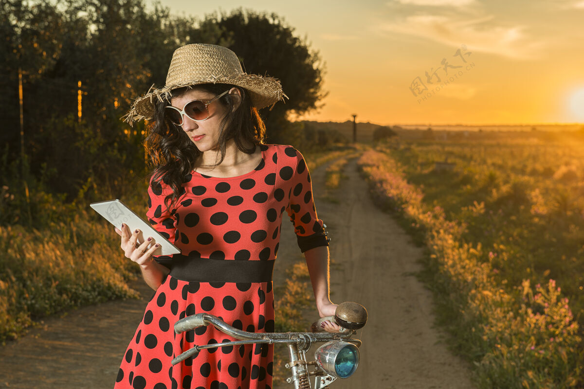 乡村美丽的年轻女子骑着自行车在户外的平板电脑上阅读电子邮件自行车数码自行车