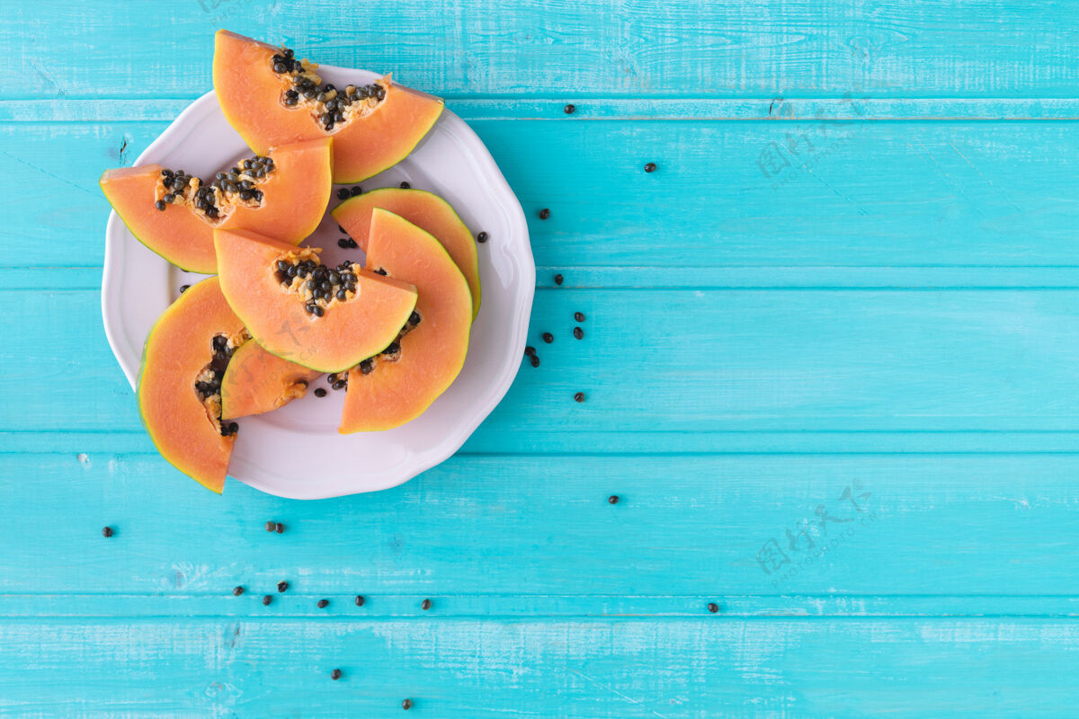 切片木瓜片放在蓝色木背景的盘子里复制空间顶视图美味素食主义者水果