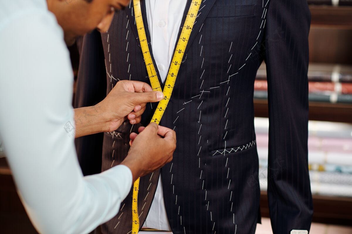 亚洲人在他的现代工作室里为客户量身定制西装裁缝测量面料