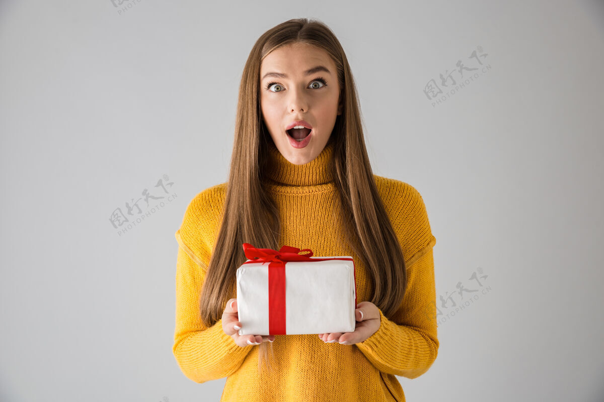 休闲一个美丽的年轻女子拿着礼物盒 被隔离在灰色的墙壁上成人震惊时尚