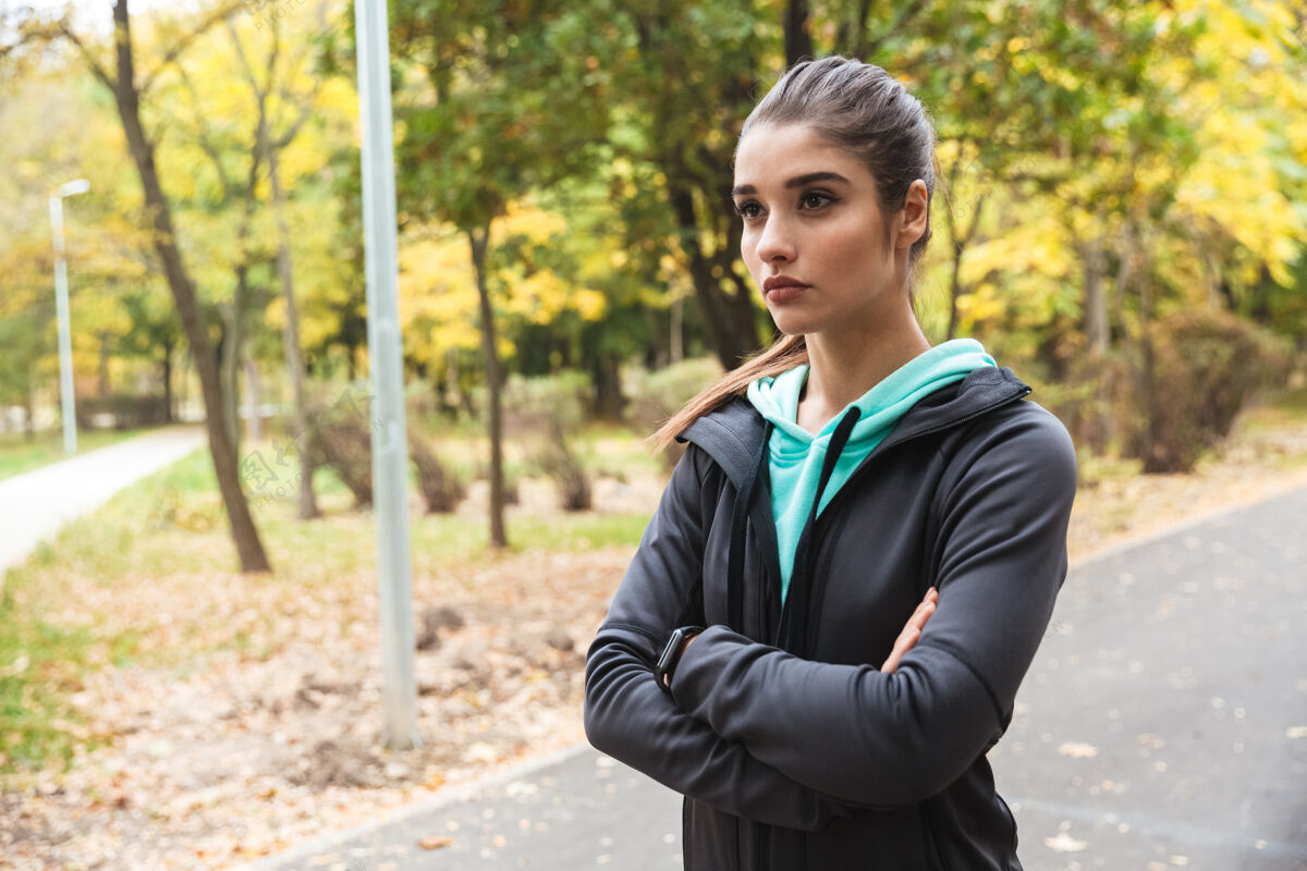 运动一个美丽的年轻漂亮的健身女跑步者在公园户外休息的形象公园练习成年人