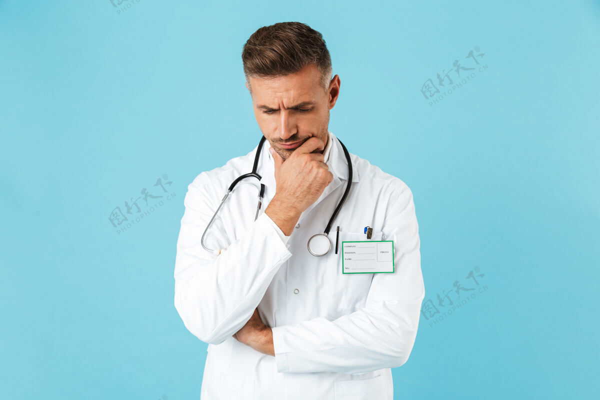 职业戴着听诊器的严肃的医生的肖像 穿着白色制服 孤立地站在蓝色的墙上医生救护车治疗