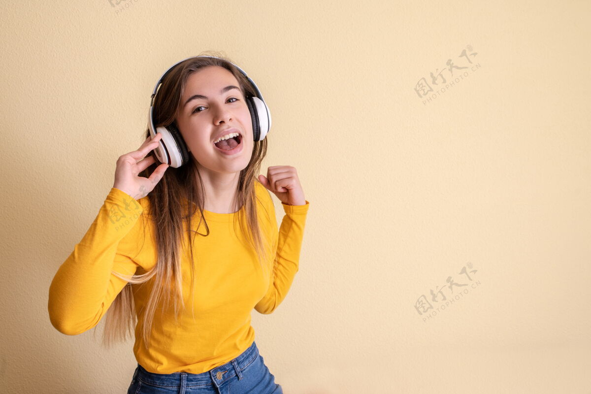 广播戴着耳机在黄色背景上跳舞的年轻女子旋律快乐音乐