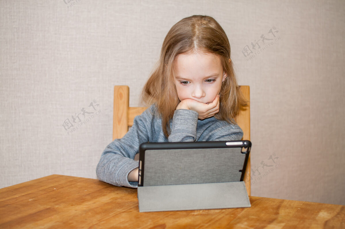 可爱小女孩正在看在线视频教程.远程培训.blog.high高质量的照片棒课人