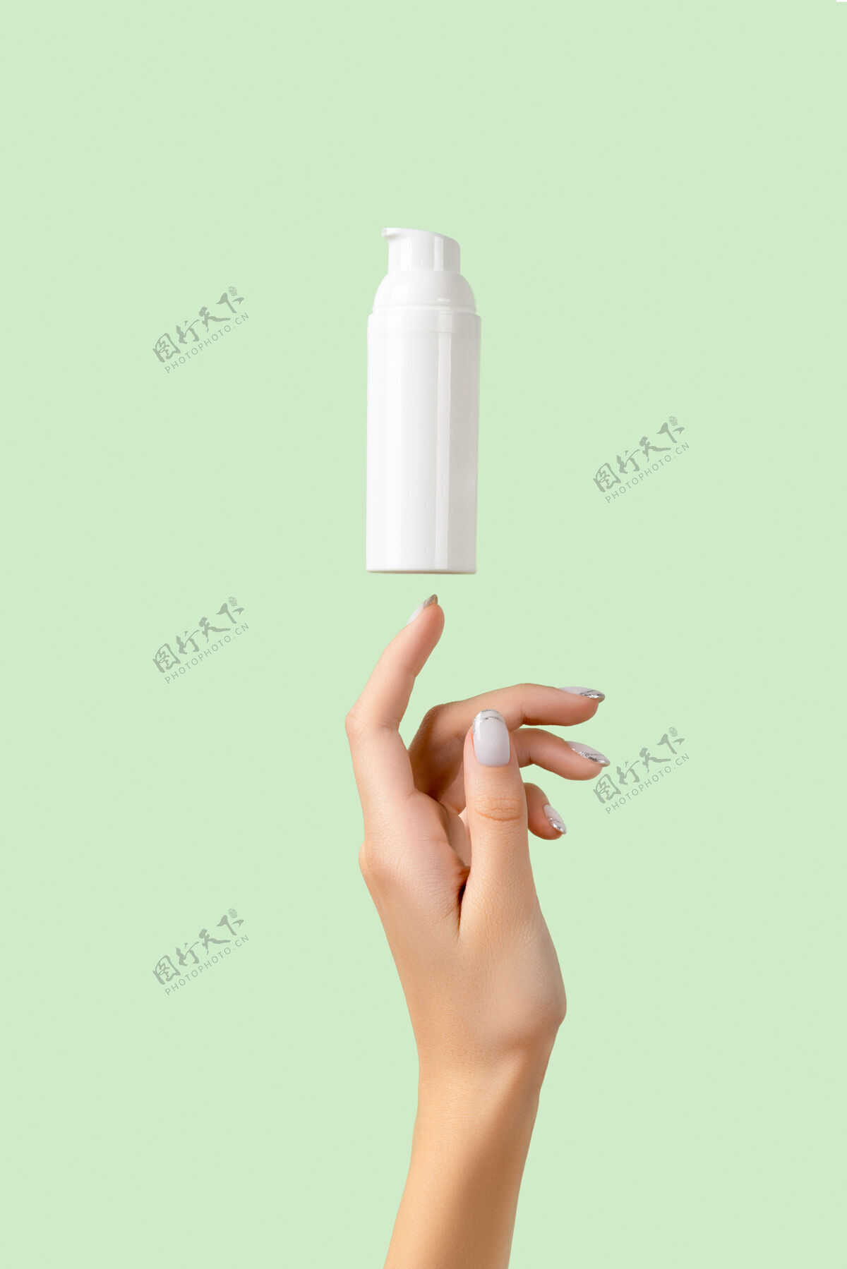 皮肤护理女人的手上有一个淡绿色的白色瓶子霜美容手
