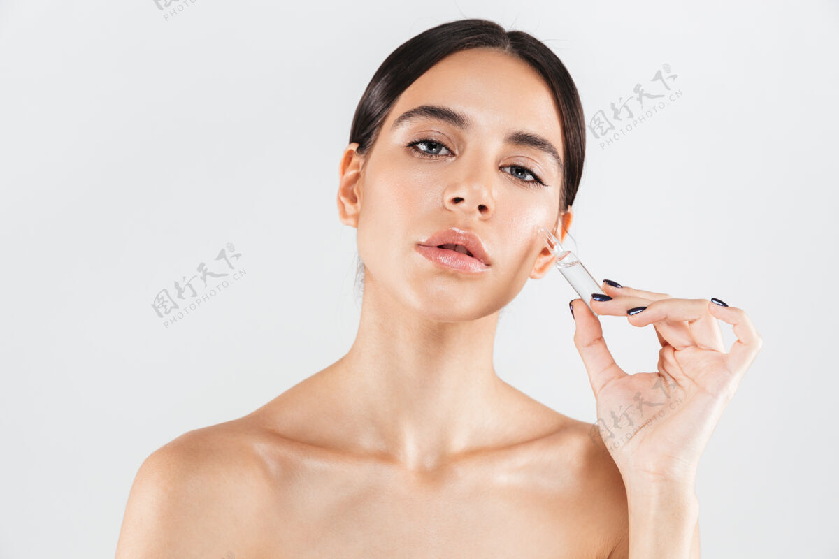 阳性美丽的肖像 一个迷人的健康的女人孤立地站在白色的墙上 显示一个玻璃胶囊与液体新鲜药物女人