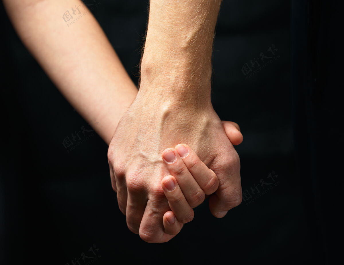社会在黑暗的背景上 男人的手牵着女人的手人类慈善救援