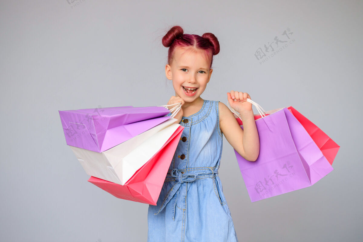 童年满足折扣快乐的小女婴微笑着拿着纸购物袋购物购物日时尚