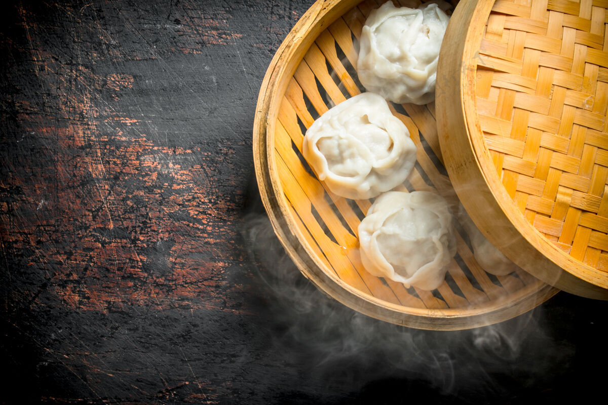 准备热腾腾的饺子螳螂放在一个竹笼里 放在一张黑色的乡村桌子上佩尔曼竹子晚餐