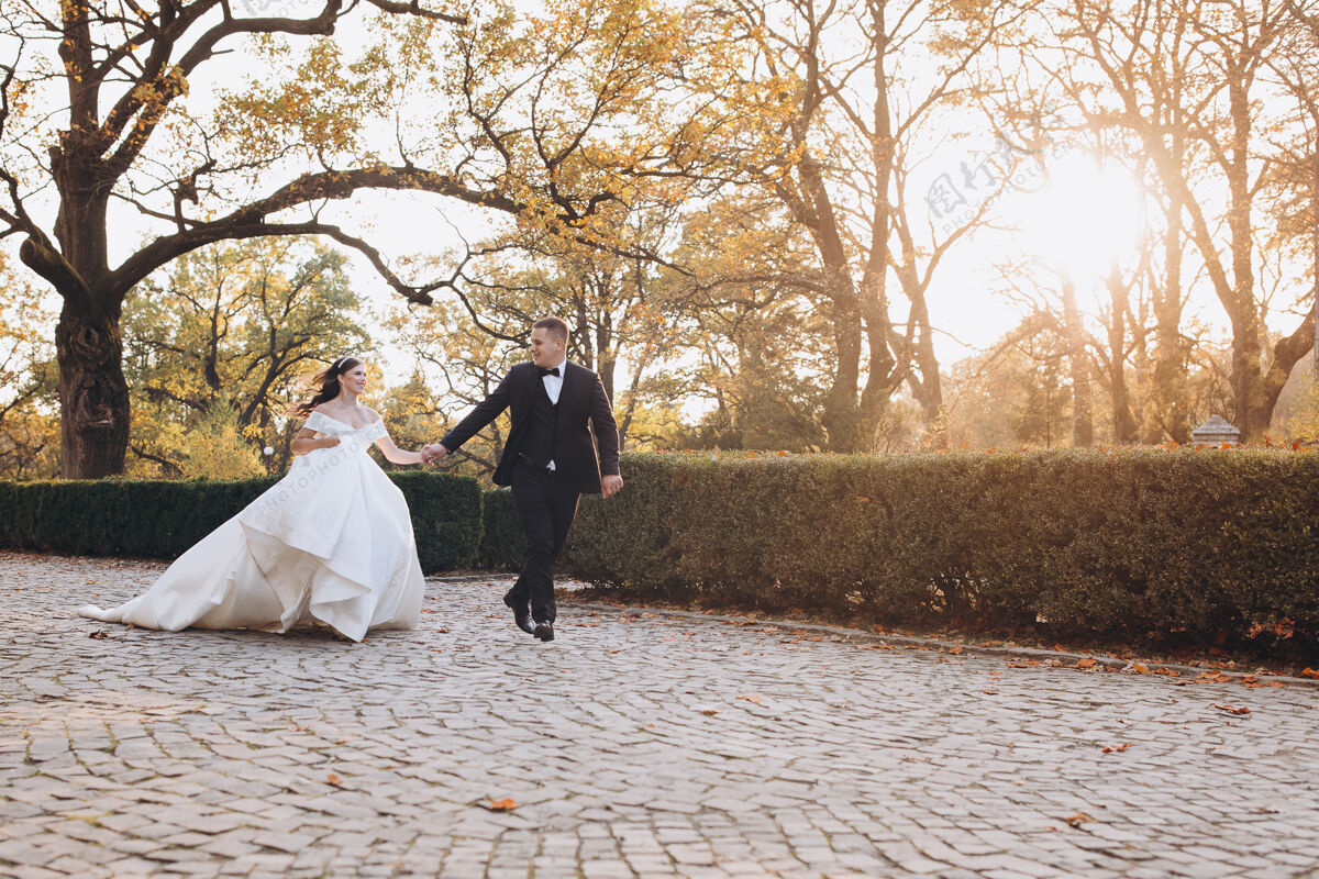亲吻快乐的新娘和新郎在他们的婚礼上快乐地一起沿着小路奔跑婚纱山户外