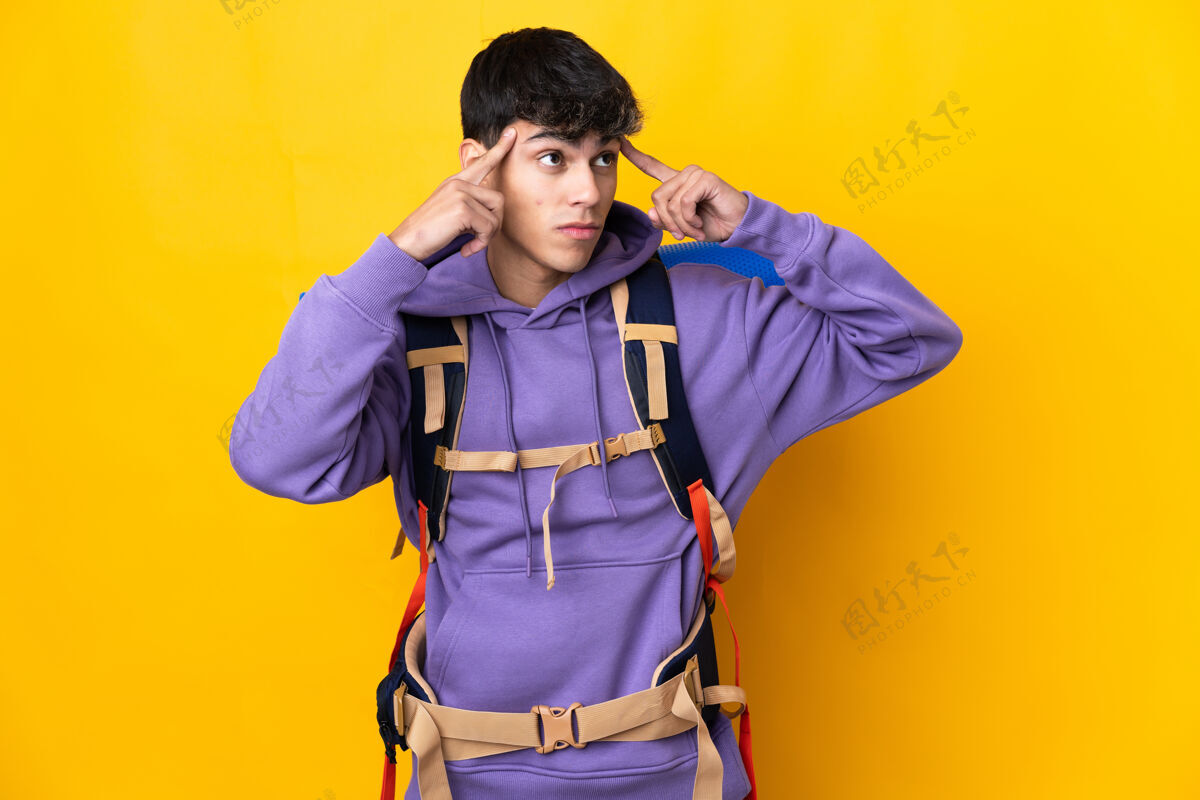 脸年轻的登山者背着一个大背包翻越孤零零的黄墙 心中充满疑惑和思考徒步旅行徒步旅行者人