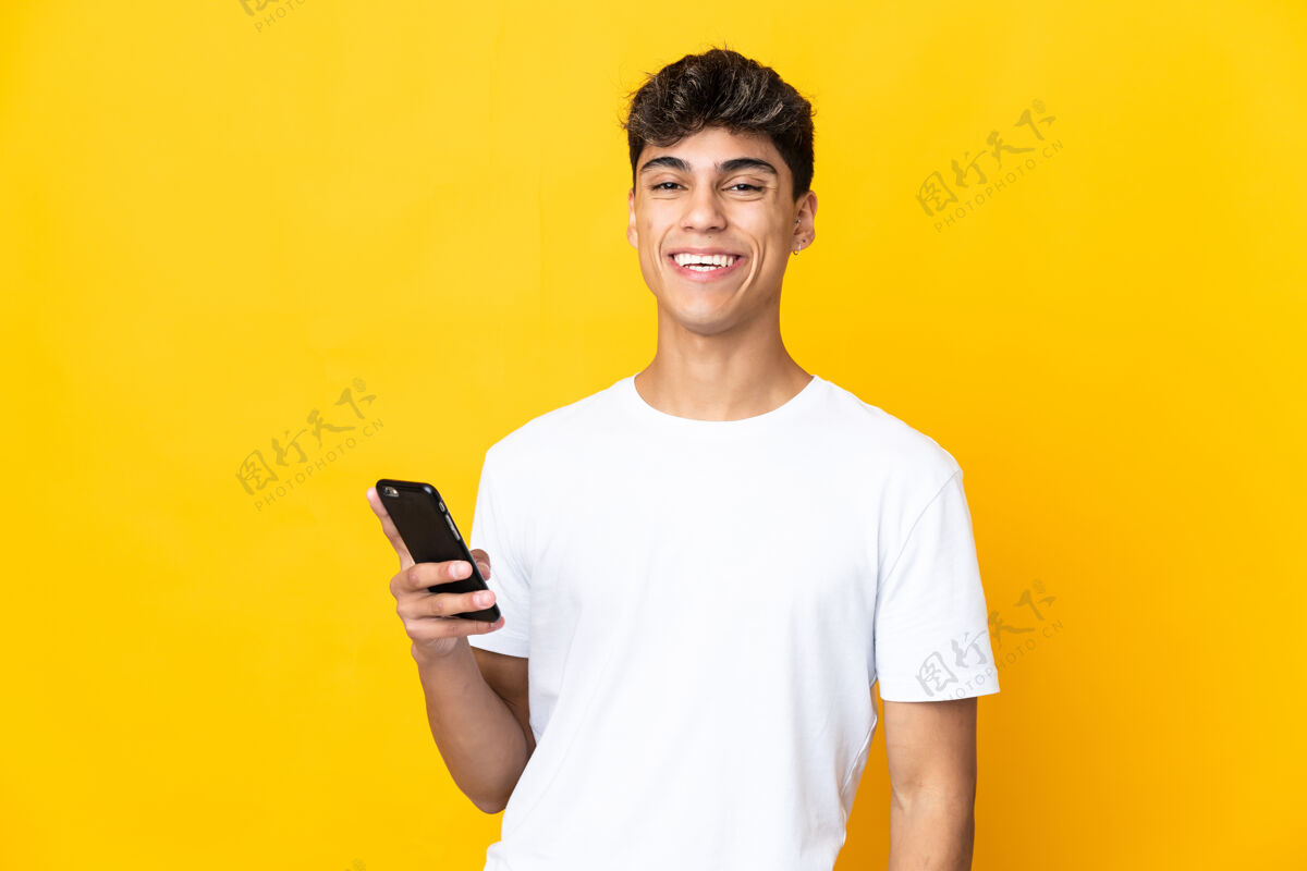 电话年轻人用手机翻越隔离的黄墙英俊男人快乐