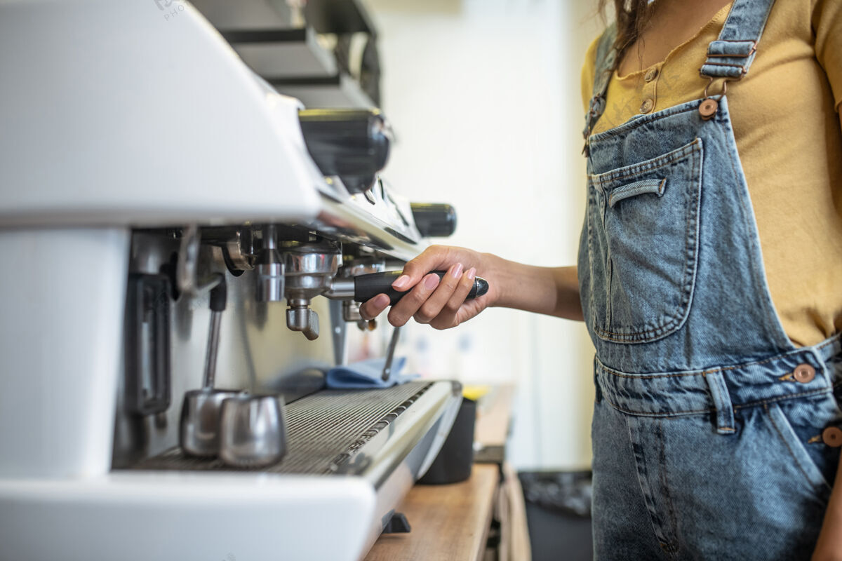 积极咖啡机器女士咖啡馆里咖啡机的把手很薄 看不到脸牛仔工作创业