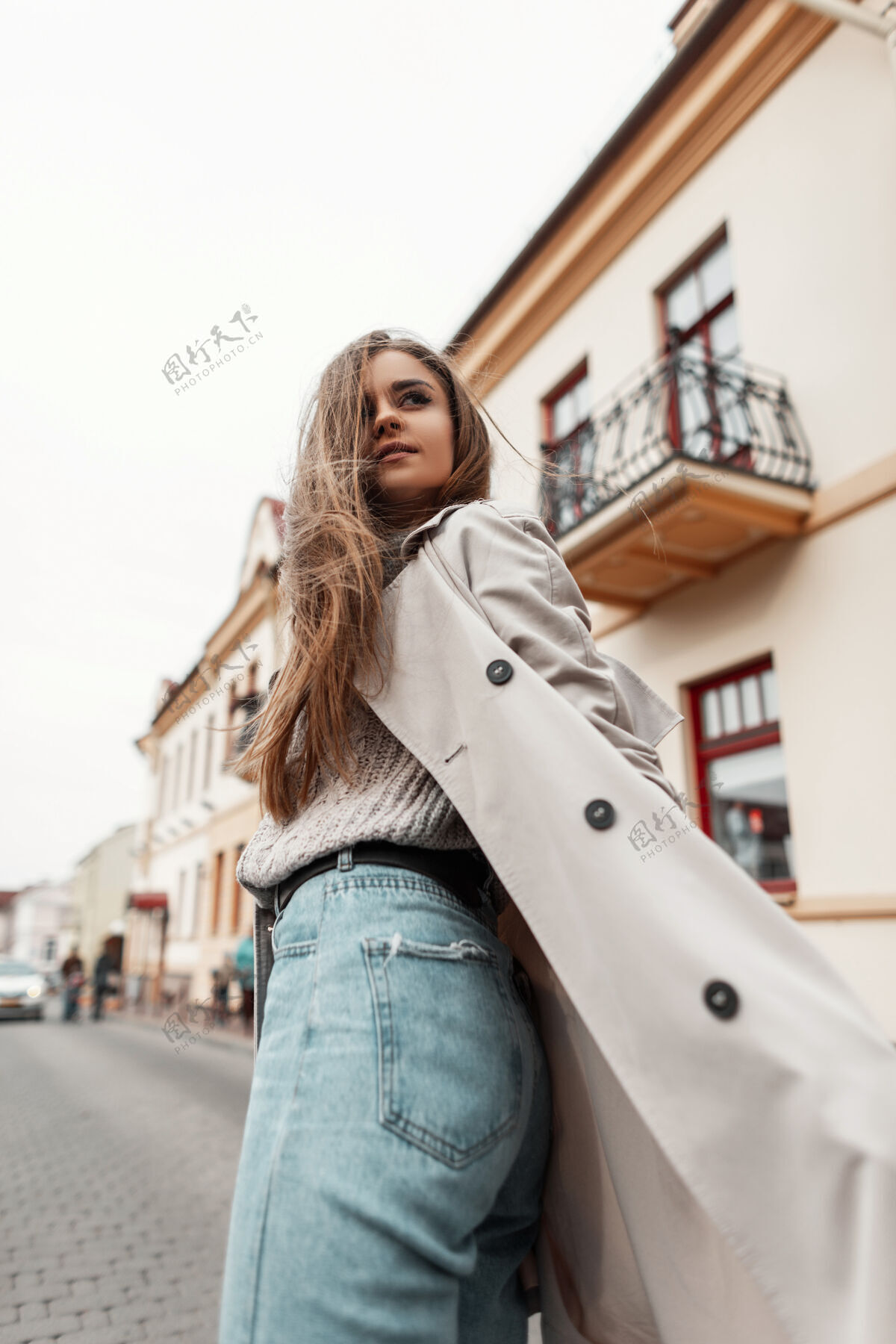 女人一个穿着风衣和针织复古毛衣的年轻女子的模特走在街上模特外套年轻