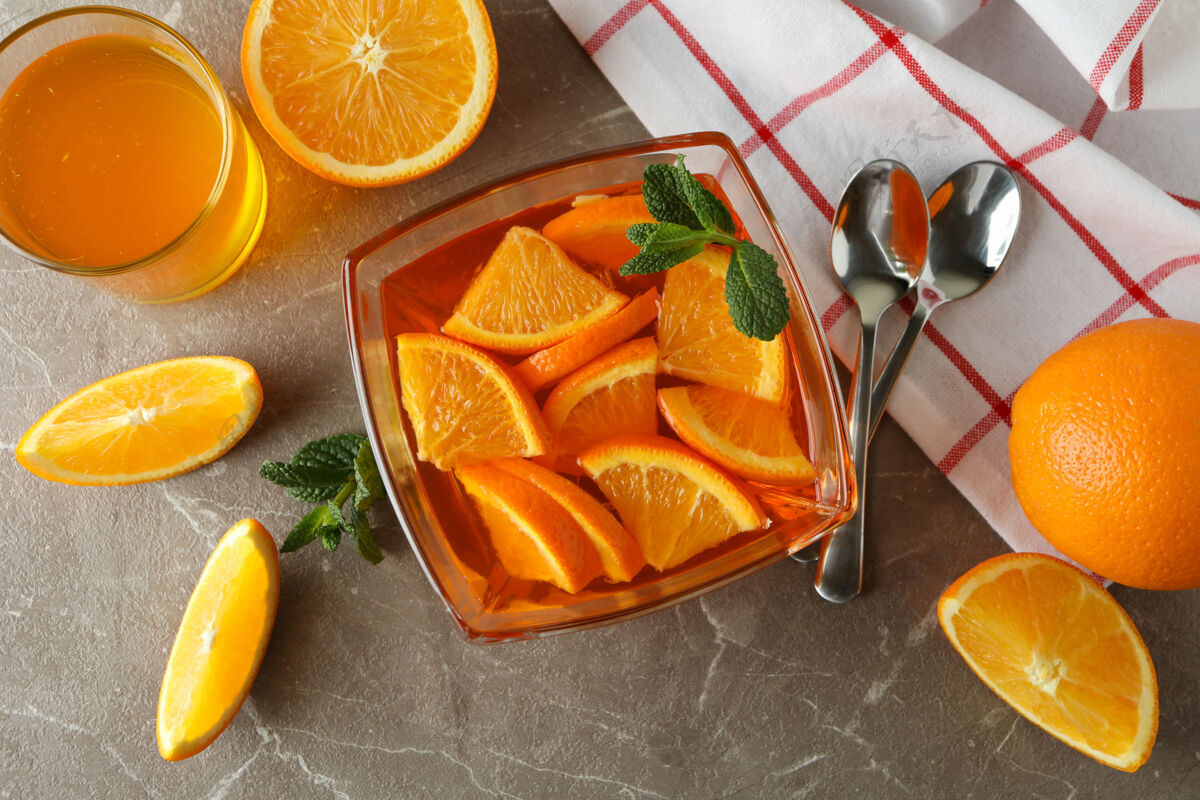 冷甜点的概念是在灰色的桌子上放一碗橘子果冻和橘子片冷美食美食