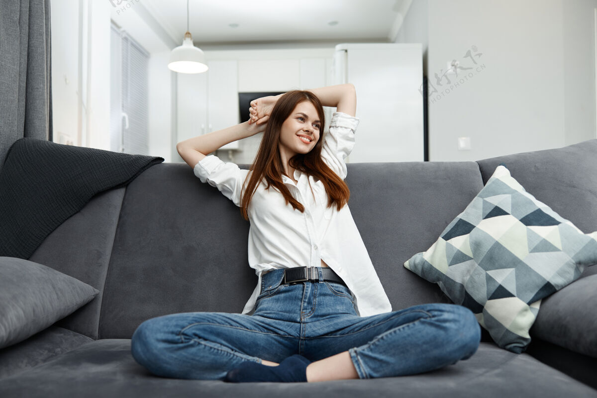 女性微笑的女人坐在沙发上 弯着腿 双臂放在脑后 舒服地休息房间沙发休闲