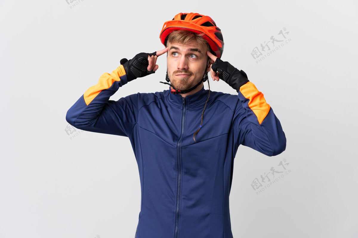 成年人年轻的骑自行车的金发男子孤立在白色背景有疑问和思考健康骑自行车的头盔