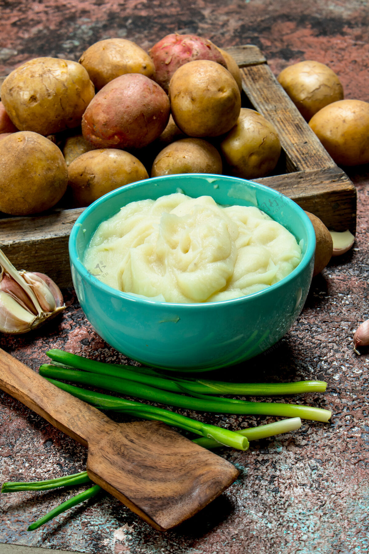绿色木桌上放着一碗土豆泥和葱牛奶土豆顶视图