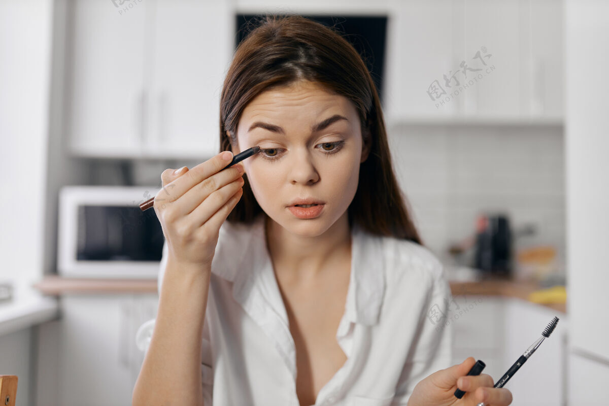 自然女模特用手拿着眼线笔在厨房里皮肤护理背景护理
