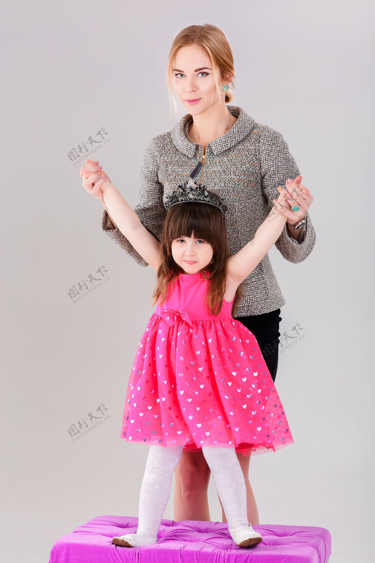 拥抱美丽的小女孩穿着粉色公主裙 头戴皇冠 美丽的母亲在灰色背景下拥抱着粉色婴儿母性